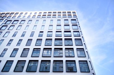 Modern Avrupa binası. Mavi gökyüzüne karşı birçok penceresi olan beyaz bir bina. Soyut mimari, modern şehir geometrisinin bir parçası.