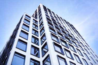 Modern Avrupa binası. Mavi gökyüzüne karşı birçok penceresi olan beyaz bir bina. Soyut mimari, modern şehir geometrisinin bir parçası.