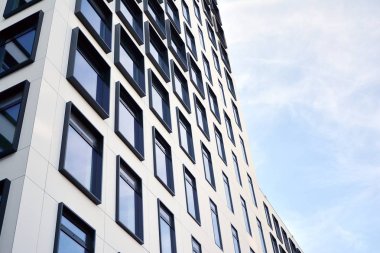 Modern Avrupa binası. Mavi gökyüzüne karşı birçok penceresi olan beyaz bir bina. Soyut mimari, modern şehir geometrisinin bir parçası.