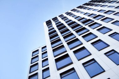 Modern Avrupa binası. Mavi gökyüzüne karşı birçok penceresi olan beyaz bir bina. Soyut mimari, modern şehir geometrisinin bir parçası.