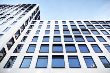 Modern Avrupa binası. Mavi gökyüzüne karşı birçok penceresi olan beyaz bir bina. Soyut mimari, modern şehir geometrisinin bir parçası.