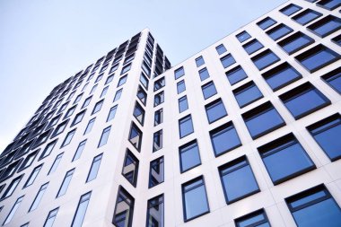 Modern Avrupa binası. Mavi gökyüzüne karşı birçok penceresi olan beyaz bir bina. Soyut mimari, modern şehir geometrisinin bir parçası.