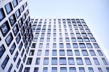 Modern Avrupa binası. Mavi gökyüzüne karşı birçok penceresi olan beyaz bir bina. Soyut mimari, modern şehir geometrisinin bir parçası.