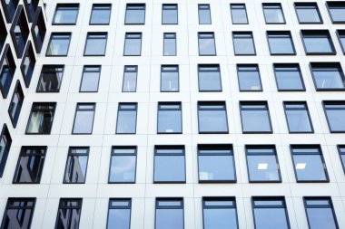 Modern Avrupa binası. Mavi gökyüzüne karşı birçok penceresi olan beyaz bir bina. Soyut mimari, modern şehir geometrisinin bir parçası.