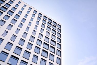 Modern Avrupa binası. Mavi gökyüzüne karşı birçok penceresi olan beyaz bir bina. Soyut mimari, modern şehir geometrisinin bir parçası.