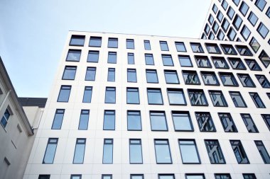 Modern Avrupa binası. Mavi gökyüzüne karşı birçok penceresi olan beyaz bir bina. Soyut mimari, modern şehir geometrisinin bir parçası.