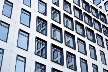 Modern Avrupa binası. Mavi gökyüzüne karşı birçok penceresi olan beyaz bir bina. Soyut mimari, modern şehir geometrisinin bir parçası.