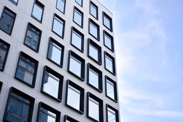 Modern European building. White building with many windows against the blue sky. Abstract architecture, fragment of modern urban geometry.