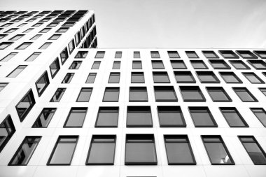 Modern Avrupa binası. Mavi gökyüzüne karşı birçok penceresi olan beyaz bir bina. Soyut mimari, modern şehir geometrisinin bir parçası. Siyah ve beyaz.