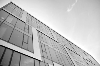 Çelik ve camdan yapılmış, mavi gökyüzü olan modern ofis duvarı. Siyah ve beyaz.