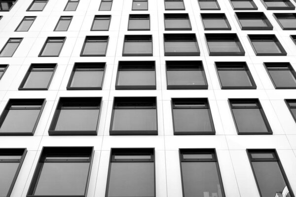 Modern European building. White building with many windows against the blue sky. Abstract architecture, fragment of modern urban geometry. Black and white.