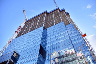 Yeni modern ofis gökdeleni bir şehirde inşa ediliyor. İnşaat sırasında cam elementlerin tamamlandığı ve beton olarak inşa edilen mimari ön cephe binası.