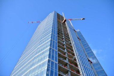 Yeni modern ofis gökdeleni bir şehirde inşa ediliyor. İnşaat sırasında cam elementlerin tamamlandığı ve beton olarak inşa edilen mimari ön cephe binası.