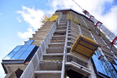Yeni modern ofis gökdeleni bir şehirde inşa ediliyor. İnşaat sırasında cam elementlerin tamamlandığı ve beton olarak inşa edilen mimari ön cephe binası.