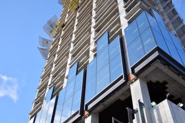 Yeni modern ofis gökdeleni bir şehirde inşa ediliyor. İnşaat sırasında cam elementlerin tamamlandığı ve beton olarak inşa edilen mimari ön cephe binası.