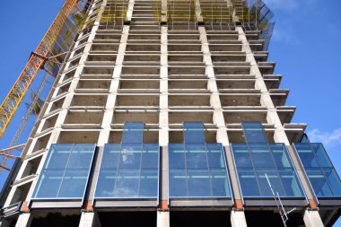 Yeni modern ofis gökdeleni bir şehirde inşa ediliyor. İnşaat sırasında cam elementlerin tamamlandığı ve beton olarak inşa edilen mimari ön cephe binası.