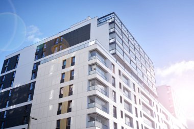 Mavi gökyüzü olan güneşli bir günde modern apartman binaları. Modern bir apartmanın ön cephesi. Güneş ışığıyla kaplı cam yüzey..