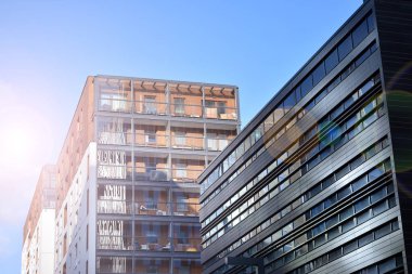 Mavi gökyüzü olan güneşli bir günde modern apartman binaları. Modern bir apartmanın ön cephesi. Güneş ışığıyla kaplı cam yüzey..