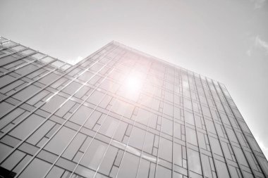 Çelik ve camdan yapılmış, mavi gökyüzü olan modern ofis duvarı. Güneş ışığıyla cam yüzey. Siyah ve beyaz.