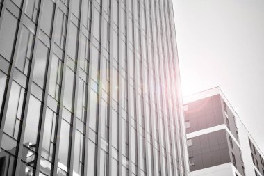 Çelik ve camdan yapılmış, mavi gökyüzü olan modern ofis duvarı. Güneş ışığıyla cam yüzey. Siyah ve beyaz.