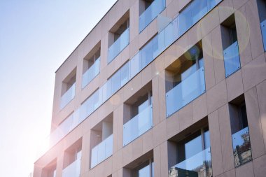 Mavi gökyüzü olan güneşli bir günde modern apartman binaları. Modern bir apartmanın ön cephesi. Güneş ışığıyla cam yüzey.