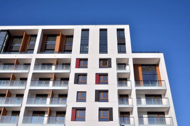 Mavi gökyüzü olan güneşli bir günde modern apartman binaları. Modern bir apartmanın ön cephesi. Güneş ışığıyla cam yüzey.