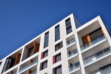 Mavi gökyüzü olan güneşli bir günde modern apartman binaları. Modern bir apartmanın ön cephesi. Güneş ışığıyla cam yüzey.