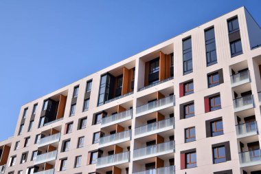 Mavi gökyüzü olan güneşli bir günde modern apartman binaları. Modern bir apartmanın ön cephesi. Güneş ışığıyla cam yüzey.