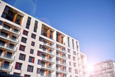 Mavi gökyüzü olan güneşli bir günde modern apartman binaları. Modern bir apartmanın ön cephesi. Güneş ışığıyla cam yüzey.