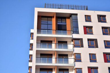 Mavi gökyüzü olan güneşli bir günde modern apartman binaları. Modern bir apartmanın ön cephesi. Güneş ışığıyla cam yüzey.