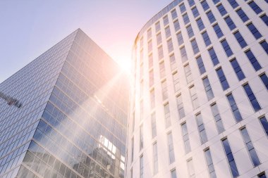 Güneş ışınları kentsel binalar üzerinde ışık etkisi yaratıyor. Modern ofis inşaatı, güneş ışığıyla kaplı cam yüzey. İş geçmişi. 