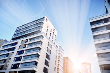 Güneş ışınları kentsel binalar üzerinde ışık etkisi yaratıyor. Düz binaları olan modern bir apartman dairesi. Yeni lüks ev ve ev kompleksinin ayrıntıları. 