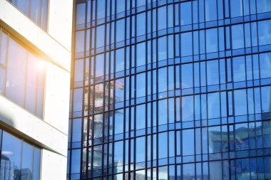 Güneş ışınları kentsel binalar üzerinde ışık etkisi yaratıyor. Modern ofis inşaatı, güneş ışığıyla kaplı cam yüzey. İş geçmişi. 