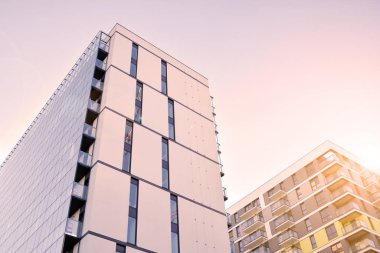 Güneş ışığı günbatımında kentsel binalar üzerinde ışık etkisi yaratır. Düz binaları olan modern bir apartman dairesi. Yeni lüks ev ve ev kompleksinin ayrıntıları. 
