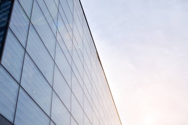 Güneş ışınları kentsel binalar üzerinde ışık etkisi yaratıyor. Modern cam ve beton binaya bakmanın soyut görüntüsü. Ofis binasının mimari dış ayrıntıları.