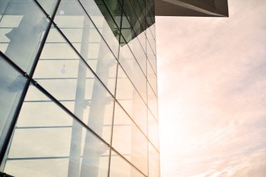 Güneş ışınları kentsel binalar üzerinde ışık etkisi yaratıyor. Modern cam ve beton binaya bakmanın soyut görüntüsü. Ofis binasının mimari dış ayrıntıları.