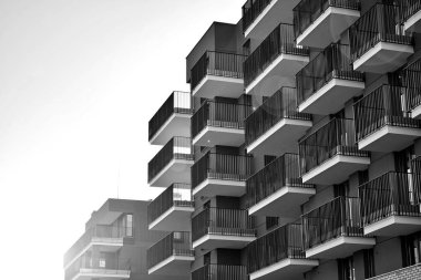 Güneş ışınları kentsel binalar üzerinde ışık etkisi yaratıyor. Düz binaları olan modern bir apartman dairesi. Yeni lüks ev ve kompleksin ayrıntıları. Siyah ve beyaz.