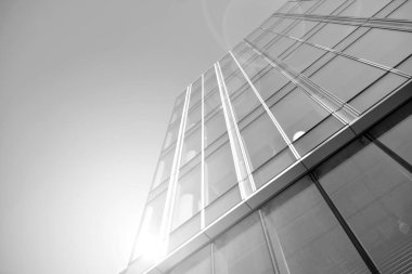 Güneş ışığı günbatımında kentsel binalar üzerinde ışık etkisi yaratır. Modern ofis inşaatı, güneş ışığıyla kaplı cam yüzey. İş geçmişi. Siyah ve beyaz.