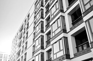 Güneş ışınları kentsel binalar üzerinde ışık etkisi yaratıyor. Düz binaları olan modern bir apartman dairesi. Yeni lüks ev ve kompleksin ayrıntıları. Siyah ve beyaz.