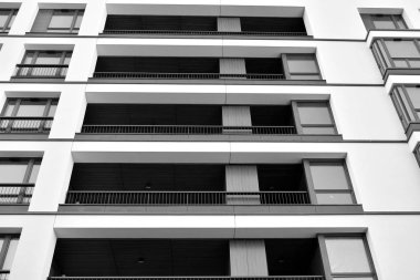 Güneş ışınları kentsel binalar üzerinde ışık etkisi yaratıyor. Düz binaları olan modern bir apartman dairesi. Yeni lüks ev ve kompleksin ayrıntıları. Siyah ve beyaz.