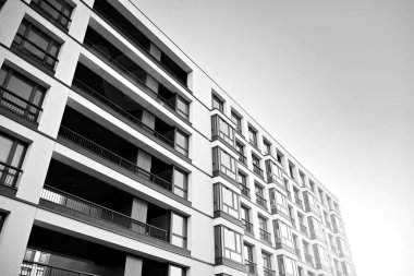 Güneş ışınları kentsel binalar üzerinde ışık etkisi yaratıyor. Düz binaları olan modern bir apartman dairesi. Yeni lüks ev ve kompleksin ayrıntıları. Siyah ve beyaz.