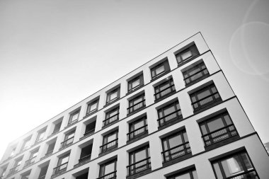 Güneş ışınları kentsel binalar üzerinde ışık etkisi yaratıyor. Düz binaları olan modern bir apartman dairesi. Yeni lüks ev ve kompleksin ayrıntıları. Siyah ve beyaz.