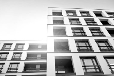 Güneş ışınları kentsel binalar üzerinde ışık etkisi yaratıyor. Düz binaları olan modern bir apartman dairesi. Yeni lüks ev ve kompleksin ayrıntıları. Siyah ve beyaz.