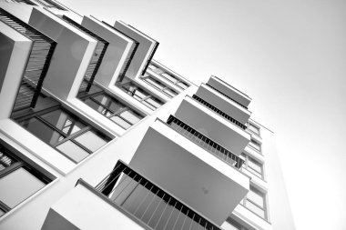 Güneş ışınları kentsel binalar üzerinde ışık etkisi yaratıyor. Düz binaları olan modern bir apartman dairesi. Yeni lüks ev ve kompleksin ayrıntıları. Siyah ve beyaz.