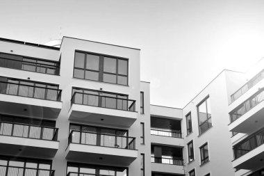 Güneş ışınları kentsel binalar üzerinde ışık etkisi yaratıyor. Düz binaları olan modern bir apartman dairesi. Yeni lüks ev ve kompleksin ayrıntıları. Siyah ve beyaz.