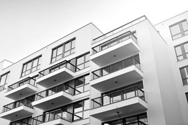 Güneş ışınları kentsel binalar üzerinde ışık etkisi yaratıyor. Düz binaları olan modern bir apartman dairesi. Yeni lüks ev ve kompleksin ayrıntıları. Siyah ve beyaz.