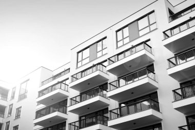 Güneş ışınları kentsel binalar üzerinde ışık etkisi yaratıyor. Düz binaları olan modern bir apartman dairesi. Yeni lüks ev ve kompleksin ayrıntıları. Siyah ve beyaz.