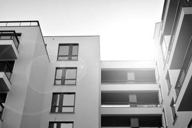 Güneş ışınları kentsel binalar üzerinde ışık etkisi yaratıyor. Düz binaları olan modern bir apartman dairesi. Yeni lüks ev ve kompleksin ayrıntıları. Siyah ve beyaz.