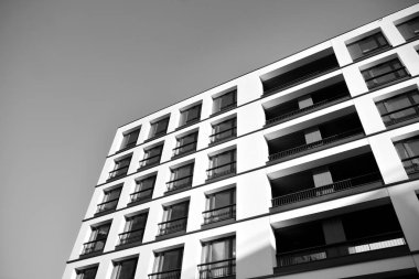 Güneş ışınları kentsel binalar üzerinde ışık etkisi yaratıyor. Düz binaları olan modern bir apartman dairesi. Yeni lüks ev ve kompleksin ayrıntıları. Siyah ve beyaz.