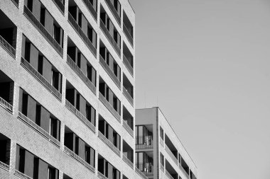 Güneş ışınları kentsel binalar üzerinde ışık etkisi yaratıyor. Düz binaları olan modern bir apartman dairesi. Yeni lüks ev ve kompleksin ayrıntıları. Siyah ve beyaz.